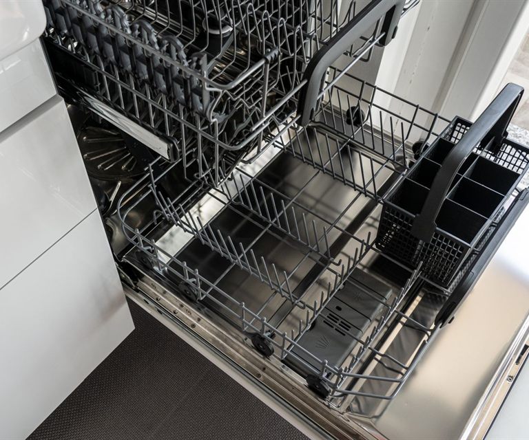 Open stainless steel dishwasher with empty racks