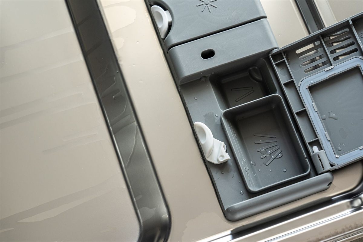 Close-up of an open detergent dispenser on the inside of a dishwasher door