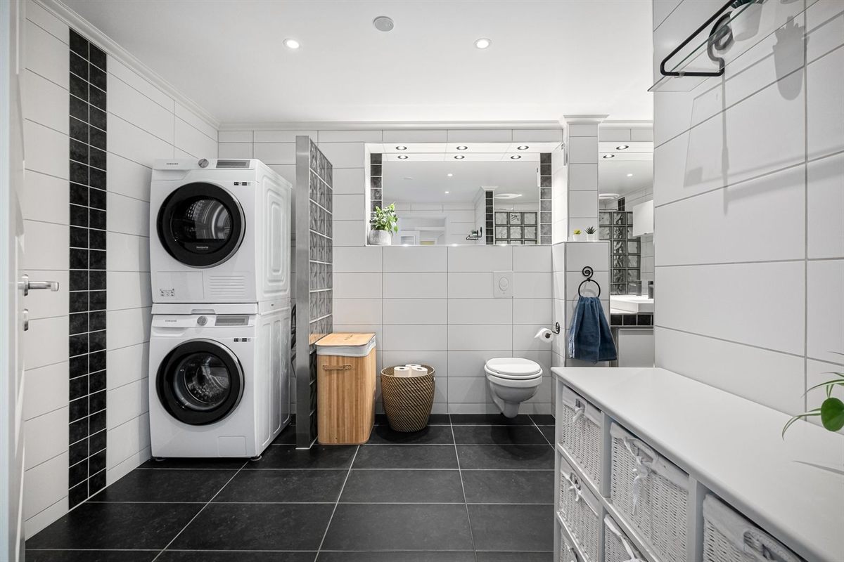 Stacked front-load washer and heat pump dryer in a tiled bathroom