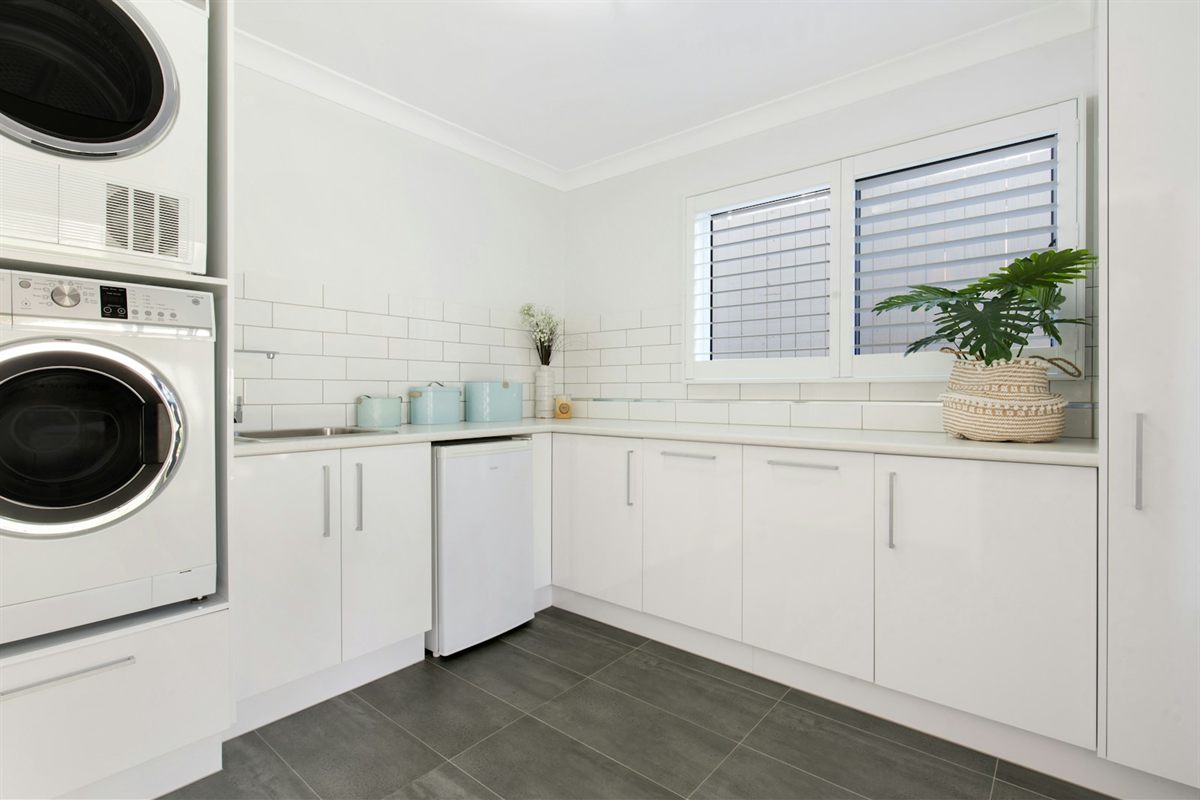 Stacked washer and dryer built into a bright white laundry room