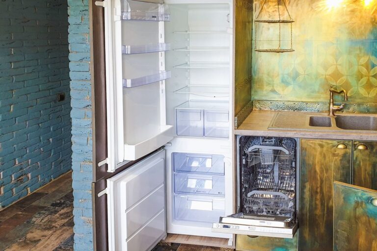Open built-in refrigerator with empty shelves and freezer drawers in a home kitchen