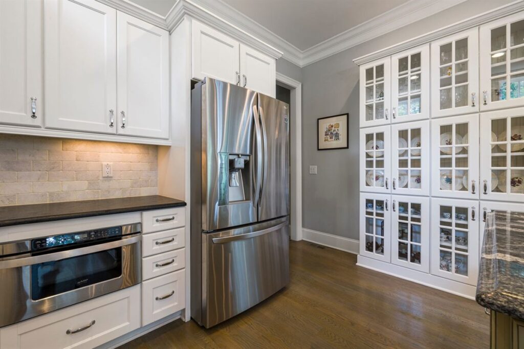 Stainless steel French door refrigerator and built-in microwave drawer in a white kitchen