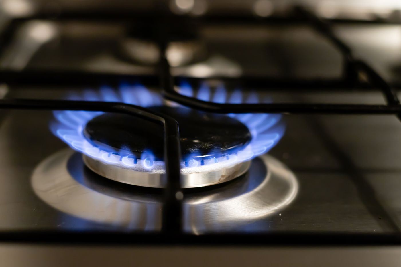 Blue flame on a stove burner under a cast-iron grate